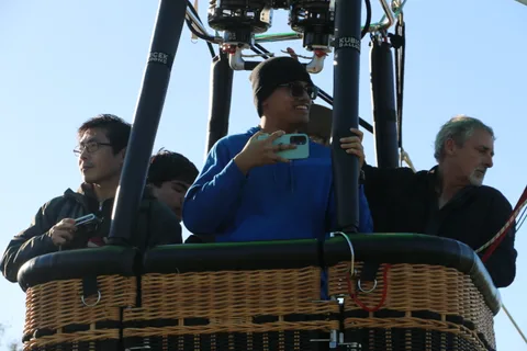 A rider in a blue hoodie looks at his phone as others wait nearby.