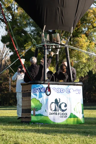 A man raises his arm near the balloon basket in a blurred candid moment.