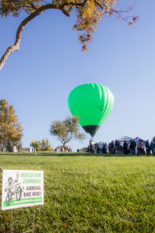 The balloon's edge peeks into frame above a distant line of people and a Zombie Bike Ride sign.