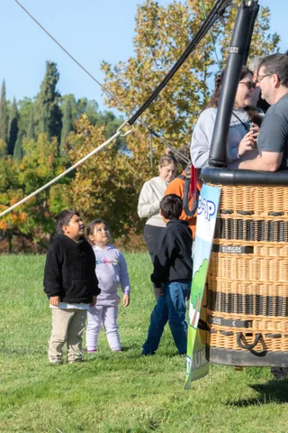 A small group including two children talks together on the park lawn.