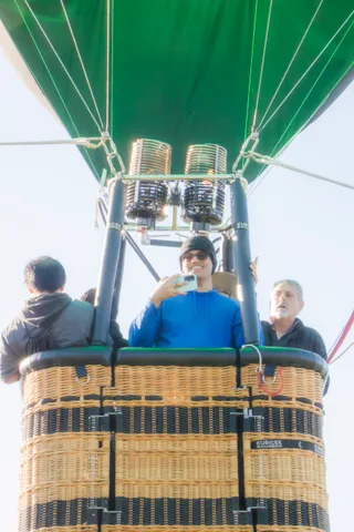 A man in blue raises his phone to photograph the view beside an older man.