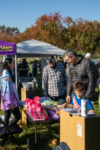 A boy reaches for a pink gift bag on a booth table.