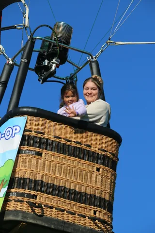 A mother and daughter wave together from the basket.