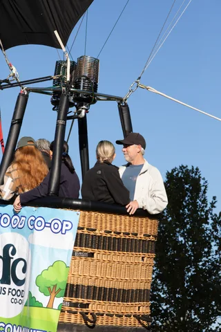 An older man in a cap and two women smile together in the basket.