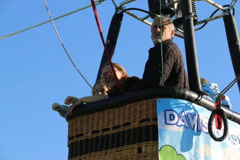 A person stands in a hot air balloon basket looking away from the camera.