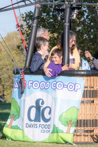 An older man embraces a boy in a purple hoodie warmly inside the basket.