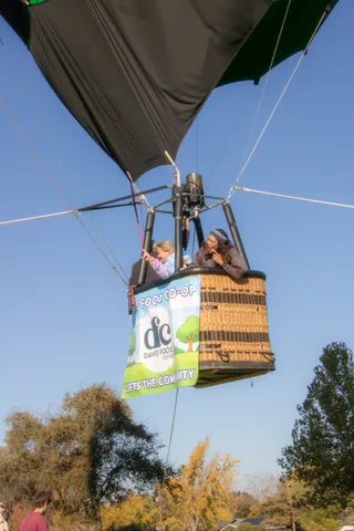 A child and a smiling woman ride in the balloon basket, caught a beat after the previous frame.