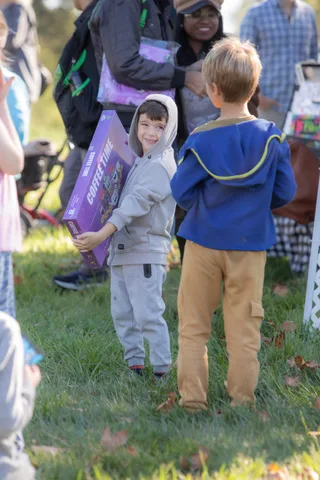 Two children in costumes stand together holding a decorated box.