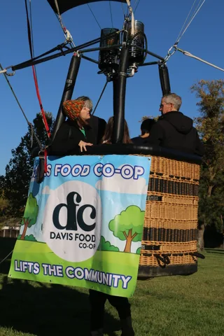 A close view of a hot air balloon basket weave beside a sponsor banner.