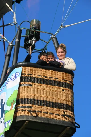 The children smile together over the basket rim.