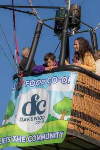 A woman in yellow and a man reach toward each other in the basket beneath the full banner.