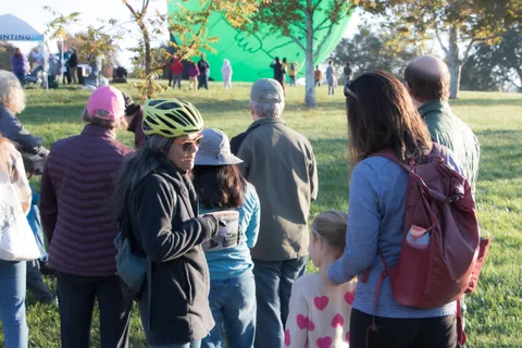 A family looks off to the side near the photo booth's green screen backdrop.