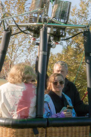 A girl in tie-dye smiles next to a woman in sunglasses at ground level.