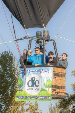 A cluster of riders smiles together as one holds up a phone in the basket.