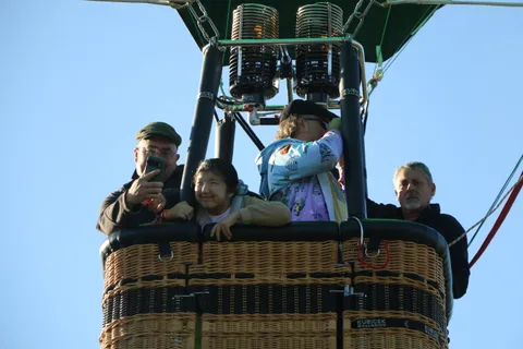 A group of riders stands together in the basket waiting to launch.