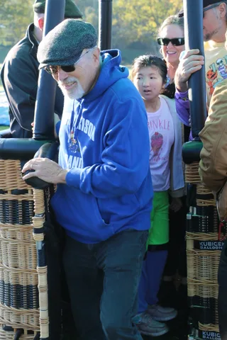 Riders wave and smile from inside the balloon basket.