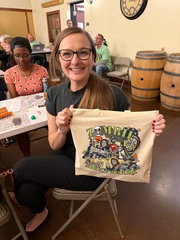 A bingo player holds up the Zombie Bike Parade tote bag she won in the raffle.