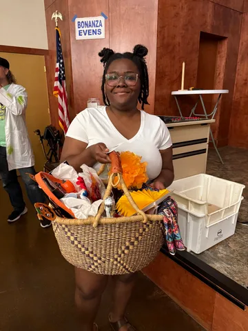 A raffle winner carries off a woven basket packed with Halloween treats and decorations.