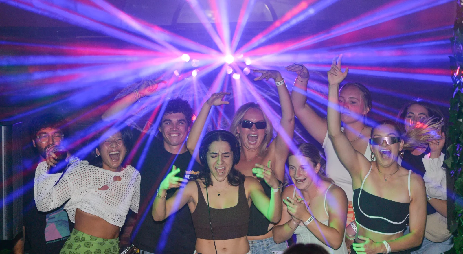 A crowd dancing under lasers at a Davis Rave Co party