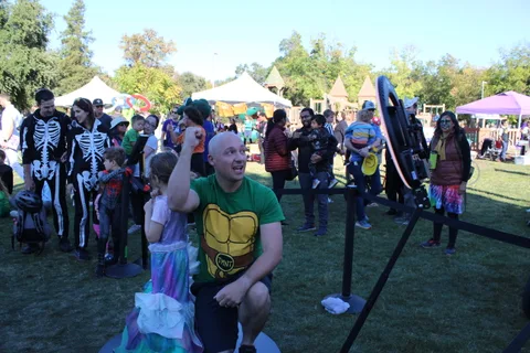 Costumed riders pose playfully around a large gong at the park festival.