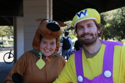 A couple dressed as Scooby-Doo and Wario share a moment at the festival.