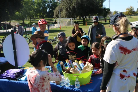 Costumed children crowd a table piled with prize bags and treats at the festival.