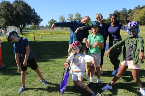 A family strikes exaggerated zombie poses with fake blood face paint on the grass.