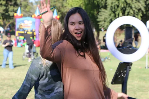 A woman laughs with her mouth open at a festival photo booth.