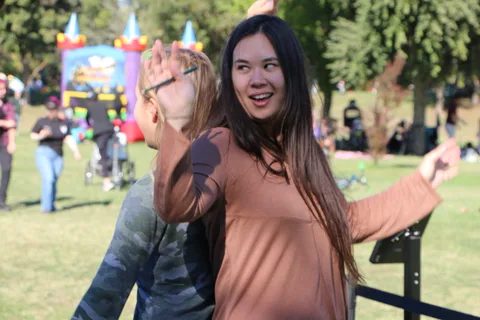 A woman with sunglasses pushed up reacts with surprise at a photo booth.