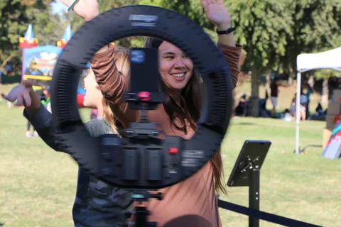 A woman smiles directly at the camera framed inside a ring light.