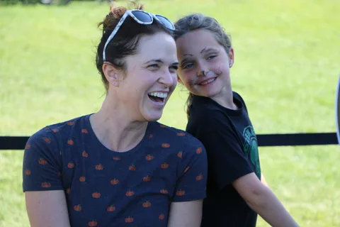 A mother and daughter in matching dark shirts laugh together at the festival.