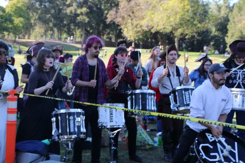 A costumed drum line performs together at the festival with snare drums in hand.