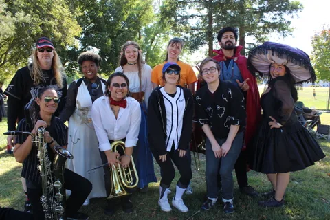A group of friends in mixed costumes pose together outdoors.
