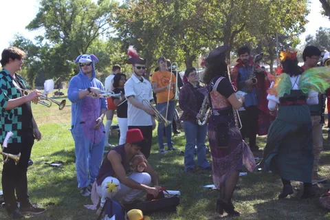 Performers in blue and purple body paint gather together at the park festival.
