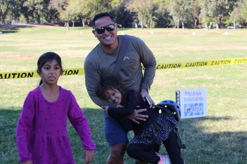 A mother and father stand together with their young child near the caution tape line.