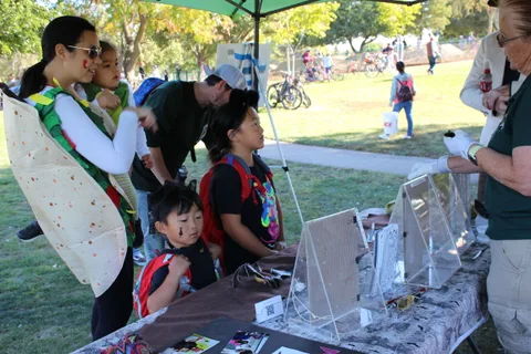 A family works on a craft activity at a booth table.