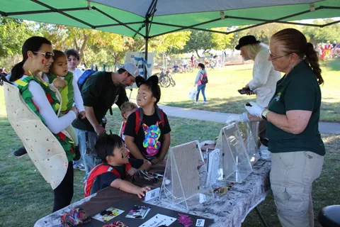 Kids work on a craft activity under a green tent.