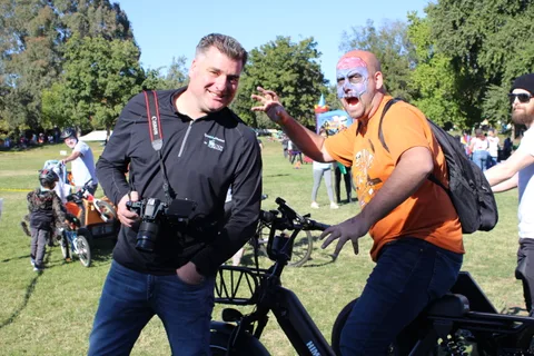 A photographer laughs while photographing a man in zombie face paint.