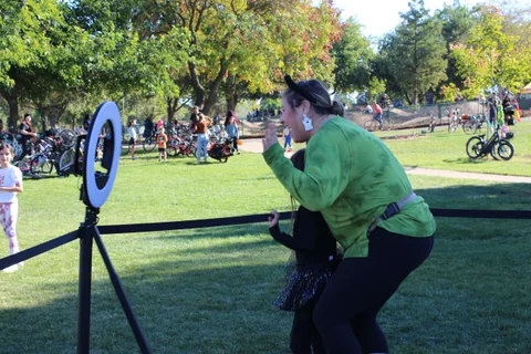 A woman in a green costume poses energetically at the photo booth.