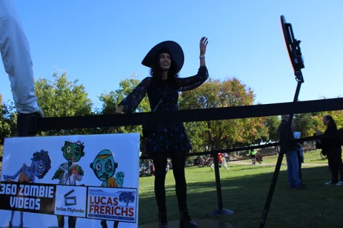 A woman in a witch costume poses on the 360 photo booth turntable.