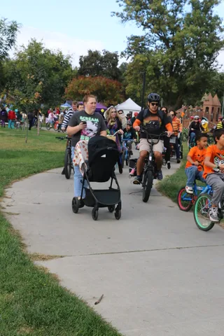 Kids in orange jail-stripe costumes ride bikes together on the parade path.