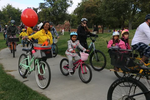 Children ride decorated bikes through the park during the event