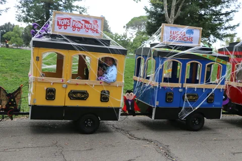 A woman waves from the window of a cobweb-decorated train car carrying Toys for Tots and campaign banners.