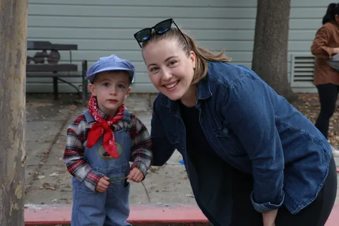 A young boy in a flat cap poses with a woman kneeling beside him.