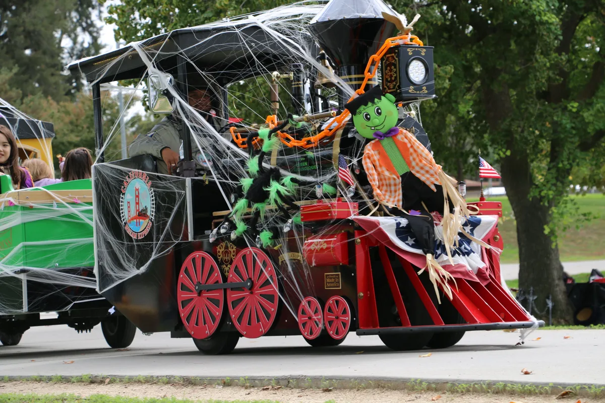 A green festival train carries riders through the park