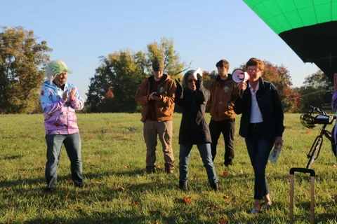 A small group stands together on the grass at a distance.