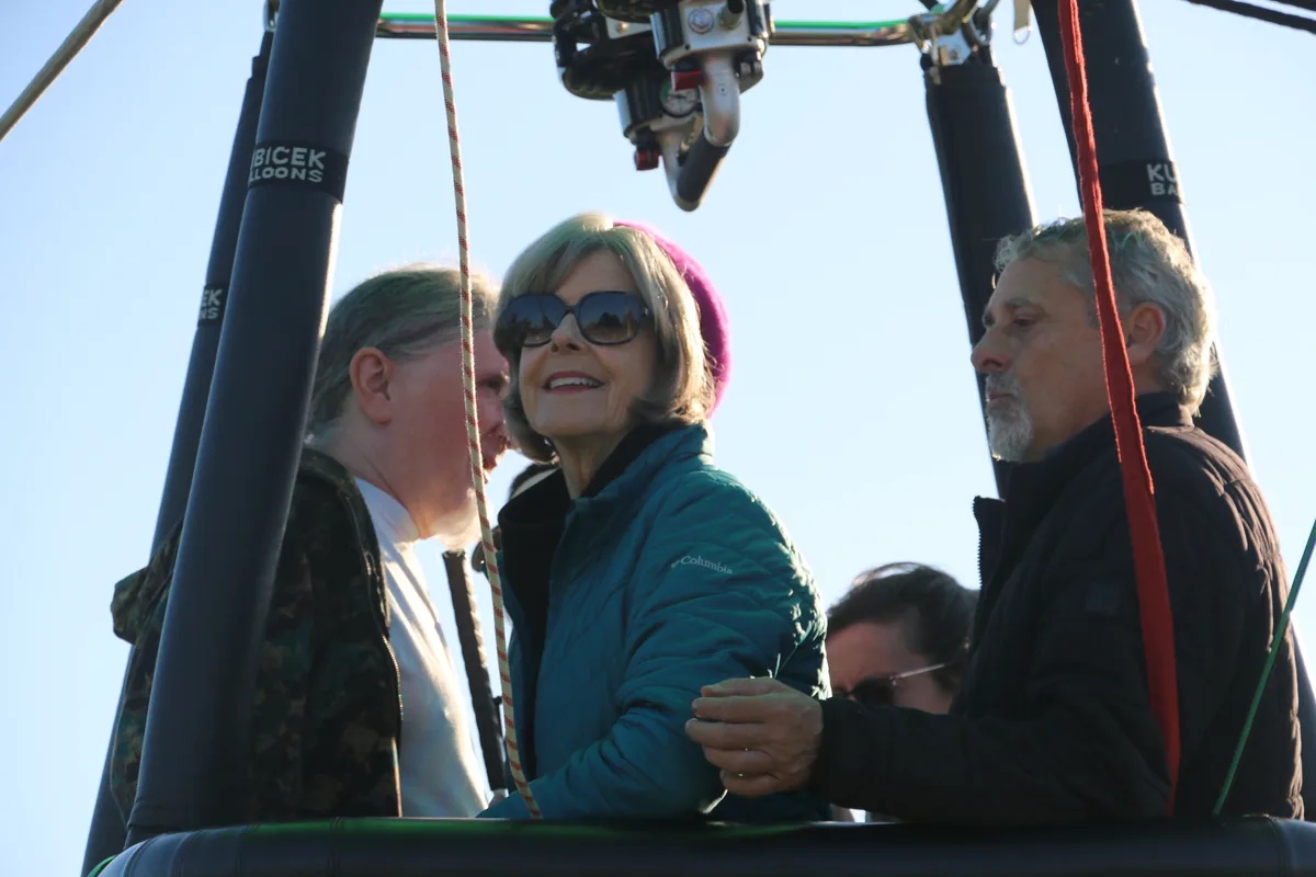 Riders smile in the balloon basket, with the Kubicek Balloons brand visible on the frame posts.