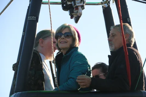 Riders smile in the balloon basket, with the Kubicek Balloons brand visible on the frame posts.