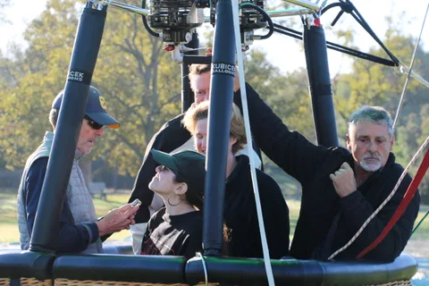 A family looks over the edge of a hot air balloon basket.