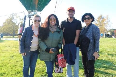Four friends pose together on the grass before the balloon launch.